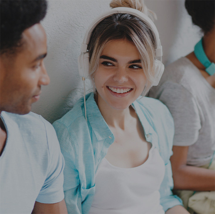 woman smiling with headphone sitting next to a friend